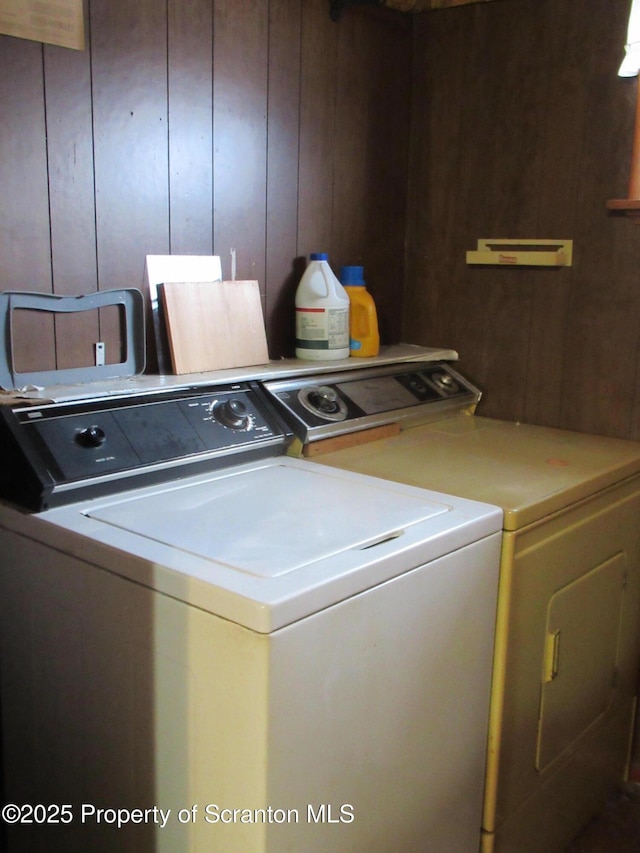 laundry area featuring wooden walls and washer and clothes dryer