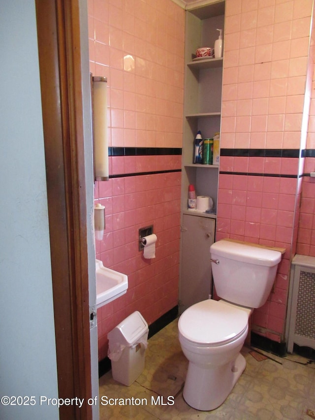 bathroom with radiator heating unit, toilet, and tile walls