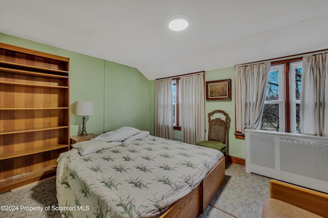 bedroom featuring radiator heating unit, multiple windows, and lofted ceiling