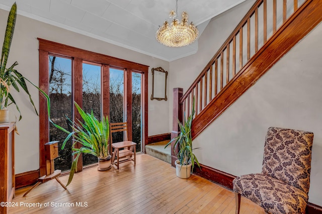 living area with light wood-type flooring, ornamental molding, and a notable chandelier