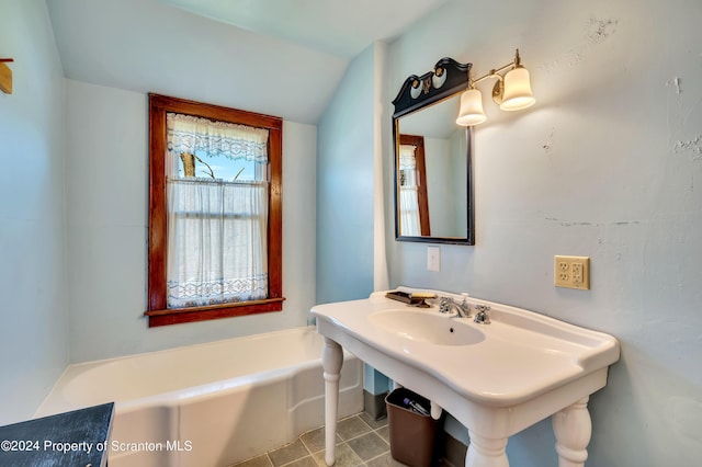 bathroom with a washtub, tile patterned flooring, and lofted ceiling