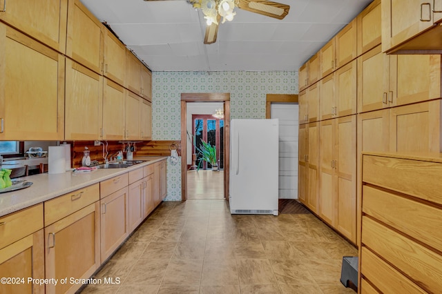 kitchen with light brown cabinets, white fridge, ceiling fan, and sink