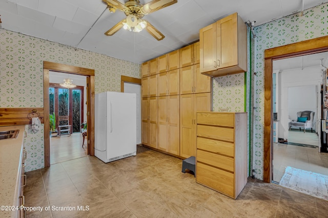 kitchen featuring light brown cabinets, white fridge, and ceiling fan with notable chandelier