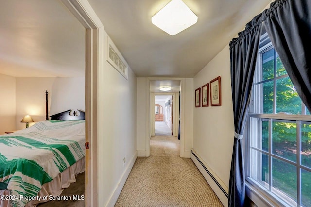 bedroom with light colored carpet and a baseboard heating unit