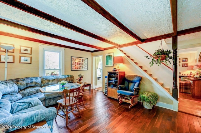 living room with dark hardwood / wood-style flooring, beamed ceiling, and a textured ceiling