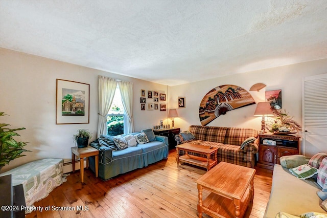 living room with a textured ceiling, light wood-type flooring, and baseboard heating