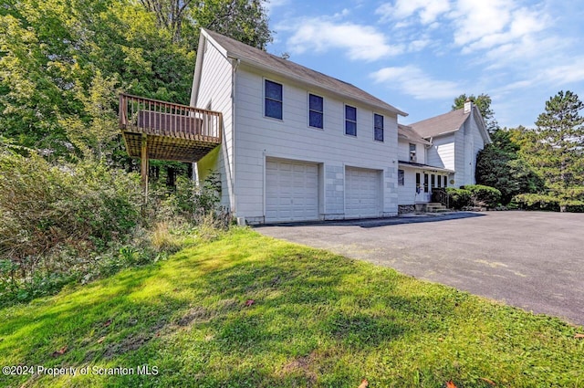 view of front of property featuring a front lawn, a deck, and a garage