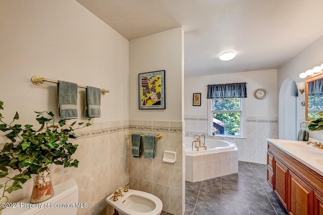 bathroom featuring tile patterned floors, tiled bath, a bidet, vanity, and tile walls