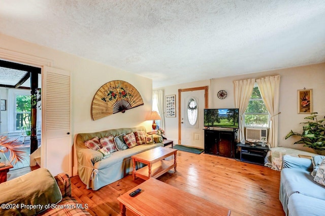 living room with a textured ceiling, light hardwood / wood-style flooring, and cooling unit