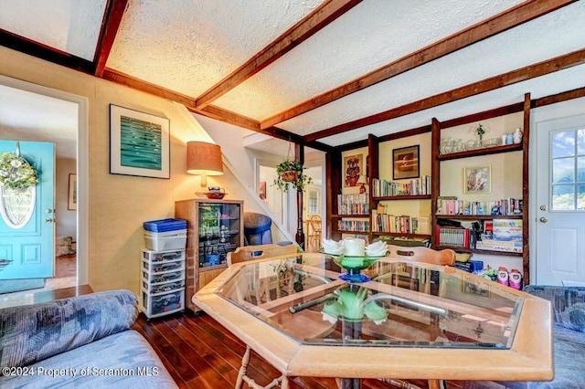 interior space featuring wood-type flooring, a textured ceiling, and beam ceiling