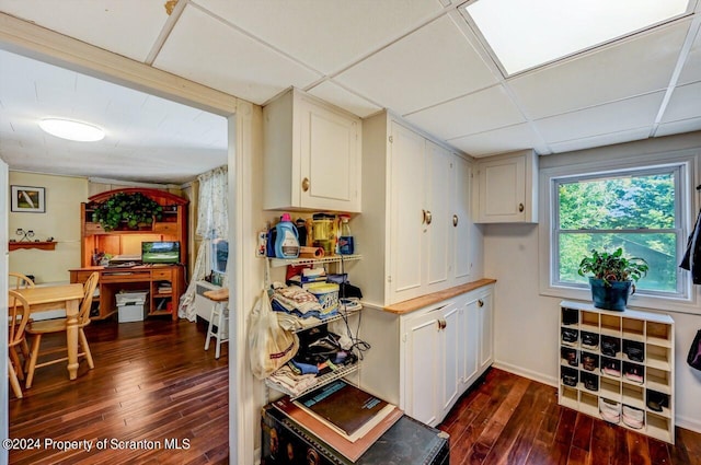 kitchen with a paneled ceiling, dark hardwood / wood-style floors, and white cabinetry