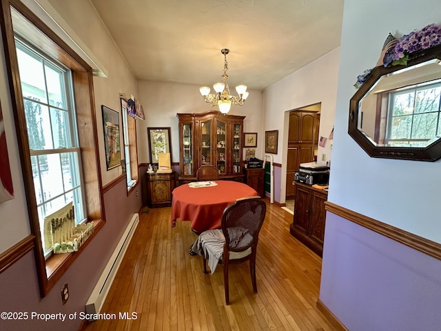 dining space with an inviting chandelier, baseboard heating, and light hardwood / wood-style floors