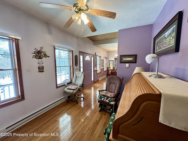 living room featuring ceiling fan, baseboard heating, and light wood-type flooring