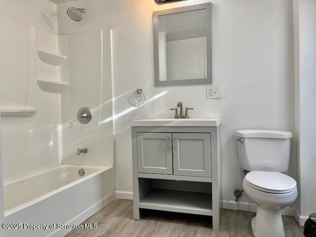 full bathroom with shower / tub combination, toilet, wood finished floors, vanity, and baseboards