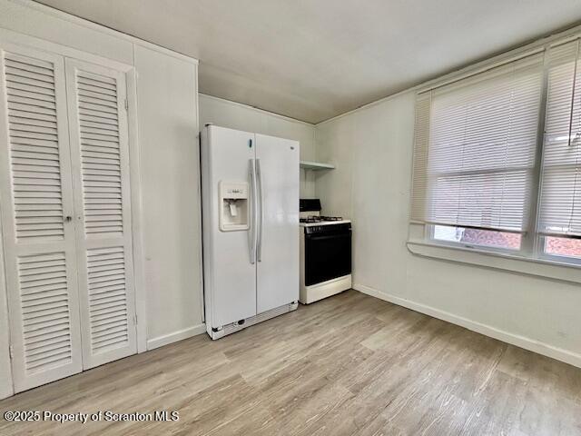 kitchen featuring light wood-type flooring, white appliances, and baseboards