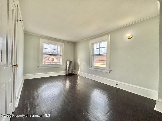 spare room featuring baseboards, ornamental molding, plenty of natural light, and radiator