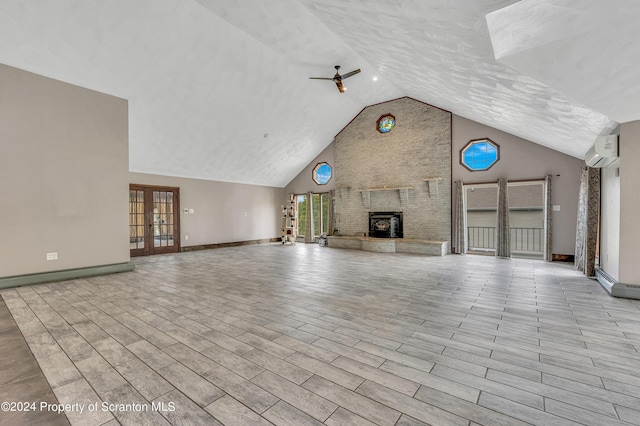 unfurnished living room featuring ceiling fan, french doors, a large fireplace, a wall mounted air conditioner, and high vaulted ceiling