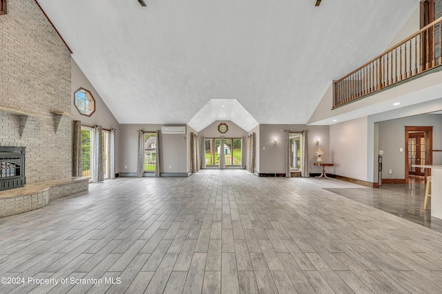 unfurnished living room with a towering ceiling, a wall unit AC, and a wood stove