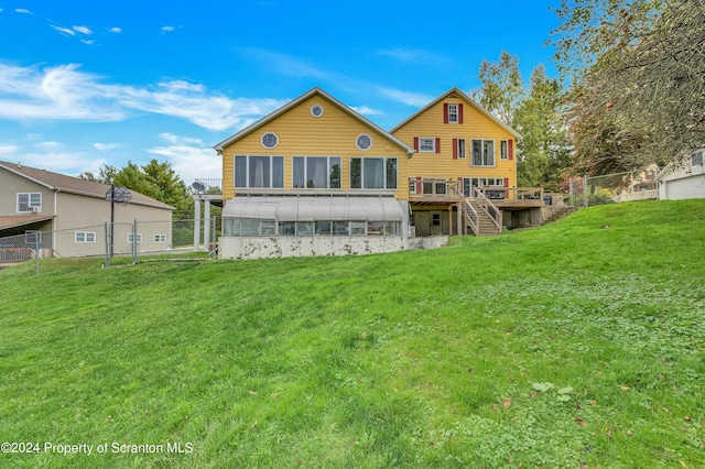 rear view of house with a lawn, a wooden deck, and a sunroom