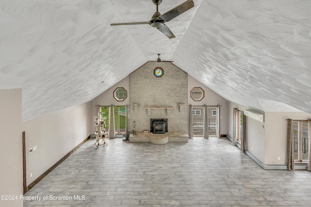 unfurnished living room with a wood stove, ceiling fan, and plenty of natural light