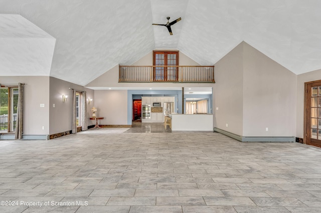 unfurnished living room featuring ceiling fan, a high ceiling, and a baseboard heating unit