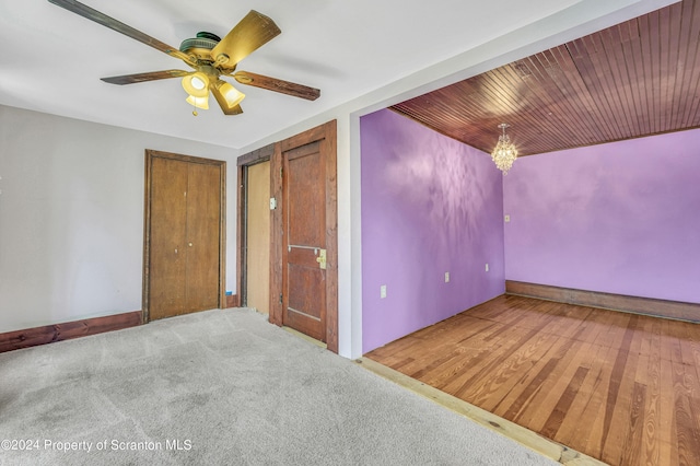 carpeted empty room with ceiling fan with notable chandelier