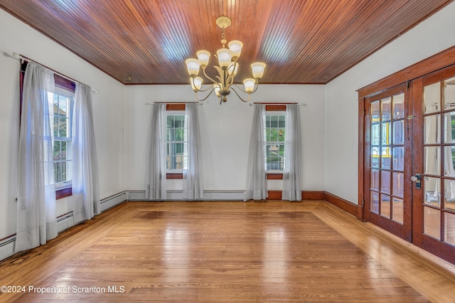 empty room featuring a notable chandelier, plenty of natural light, light hardwood / wood-style flooring, and french doors