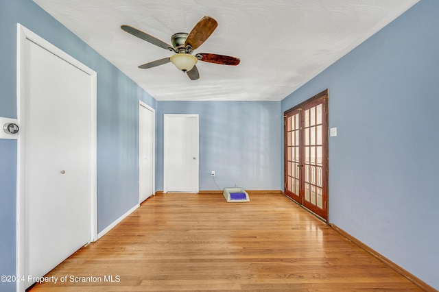 empty room with ceiling fan, light hardwood / wood-style floors, and french doors