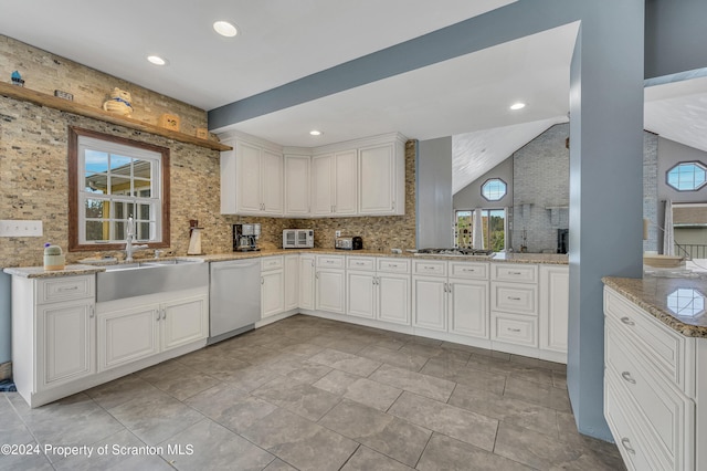 kitchen featuring white cabinets, sink, vaulted ceiling, dishwashing machine, and light stone counters