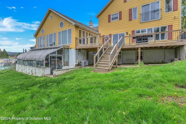 rear view of property with a wooden deck, a sunroom, a yard, and ac unit