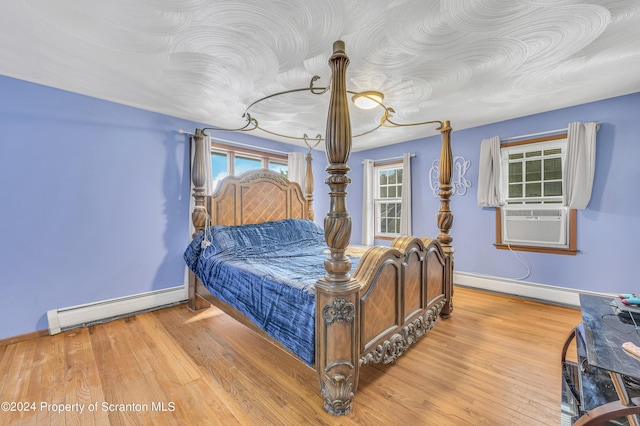 bedroom with a baseboard radiator, cooling unit, and light hardwood / wood-style floors