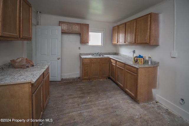 kitchen featuring light stone counters, crown molding, and sink