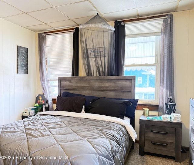 bedroom with carpet, a paneled ceiling, and multiple windows