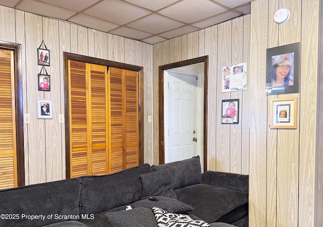 living room with a paneled ceiling and wood walls