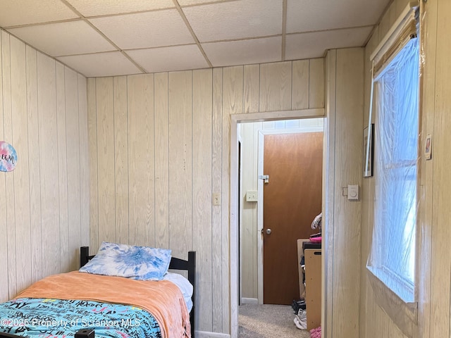 bedroom featuring a paneled ceiling, carpet, and wooden walls