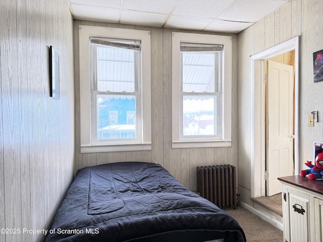 carpeted bedroom featuring a drop ceiling and radiator heating unit