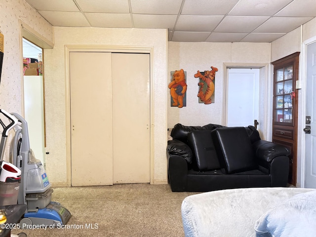 bedroom with a drop ceiling, carpet floors, and a closet