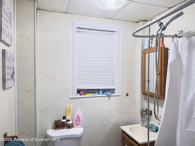 bathroom with a paneled ceiling, toilet, vanity, and walk in shower