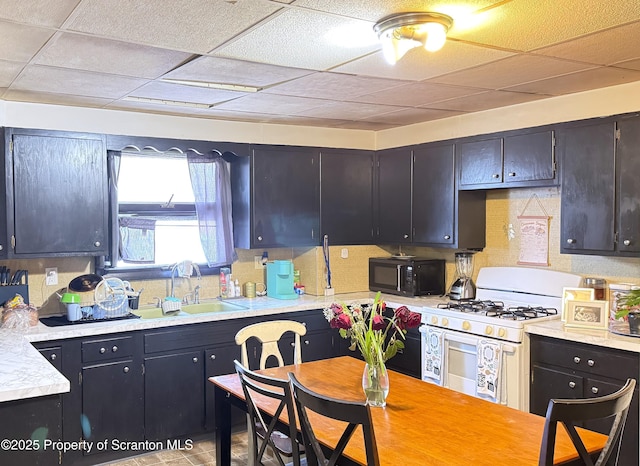 kitchen featuring dark brown cabinets, a paneled ceiling, gas range gas stove, and sink