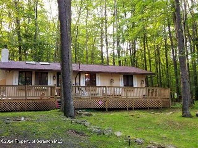 rear view of property with a lawn and a deck