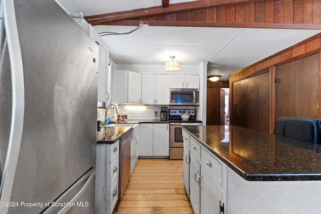 kitchen with dark stone counters, stainless steel appliances, sink, white cabinets, and a kitchen island