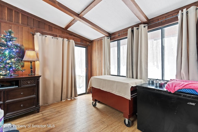 bedroom with lofted ceiling with beams and light wood-type flooring