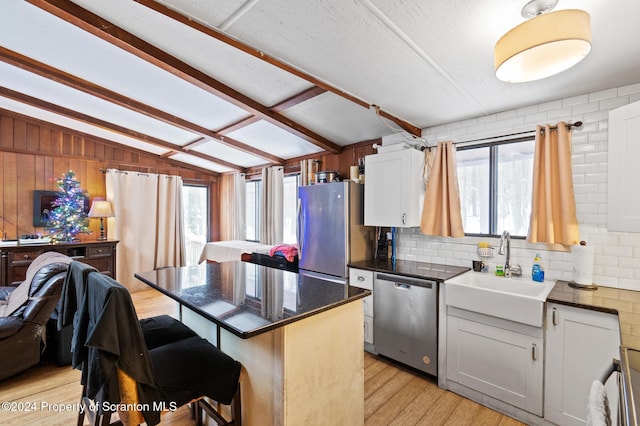 kitchen with a kitchen breakfast bar, a wealth of natural light, stainless steel appliances, vaulted ceiling, and white cabinets