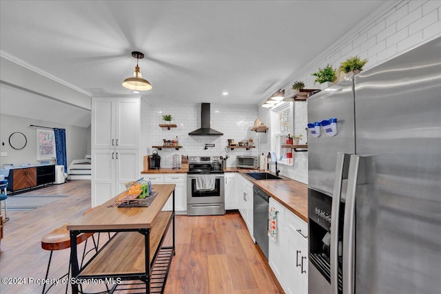 kitchen with white cabinetry, stainless steel appliances, and wall chimney range hood