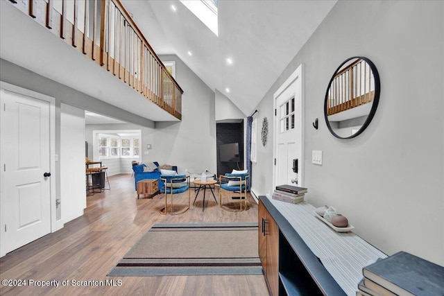 entrance foyer with a skylight, hardwood / wood-style floors, and high vaulted ceiling