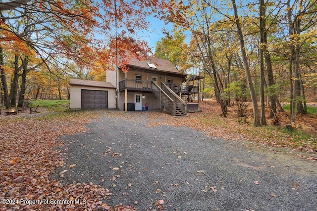 view of front of home featuring a garage, a deck, and an outbuilding