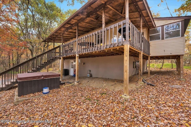 exterior space with a sunroom, central air condition unit, a wooden deck, and a hot tub