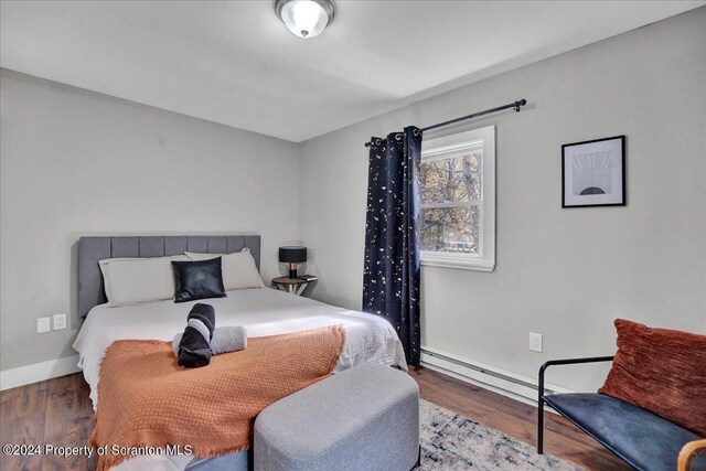 bedroom featuring dark hardwood / wood-style floors and a baseboard heating unit