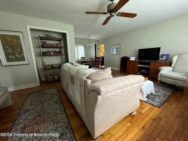living area with baseboards, wood finished floors, and a ceiling fan
