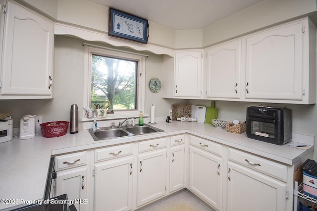 kitchen with a sink, white cabinets, and light countertops
